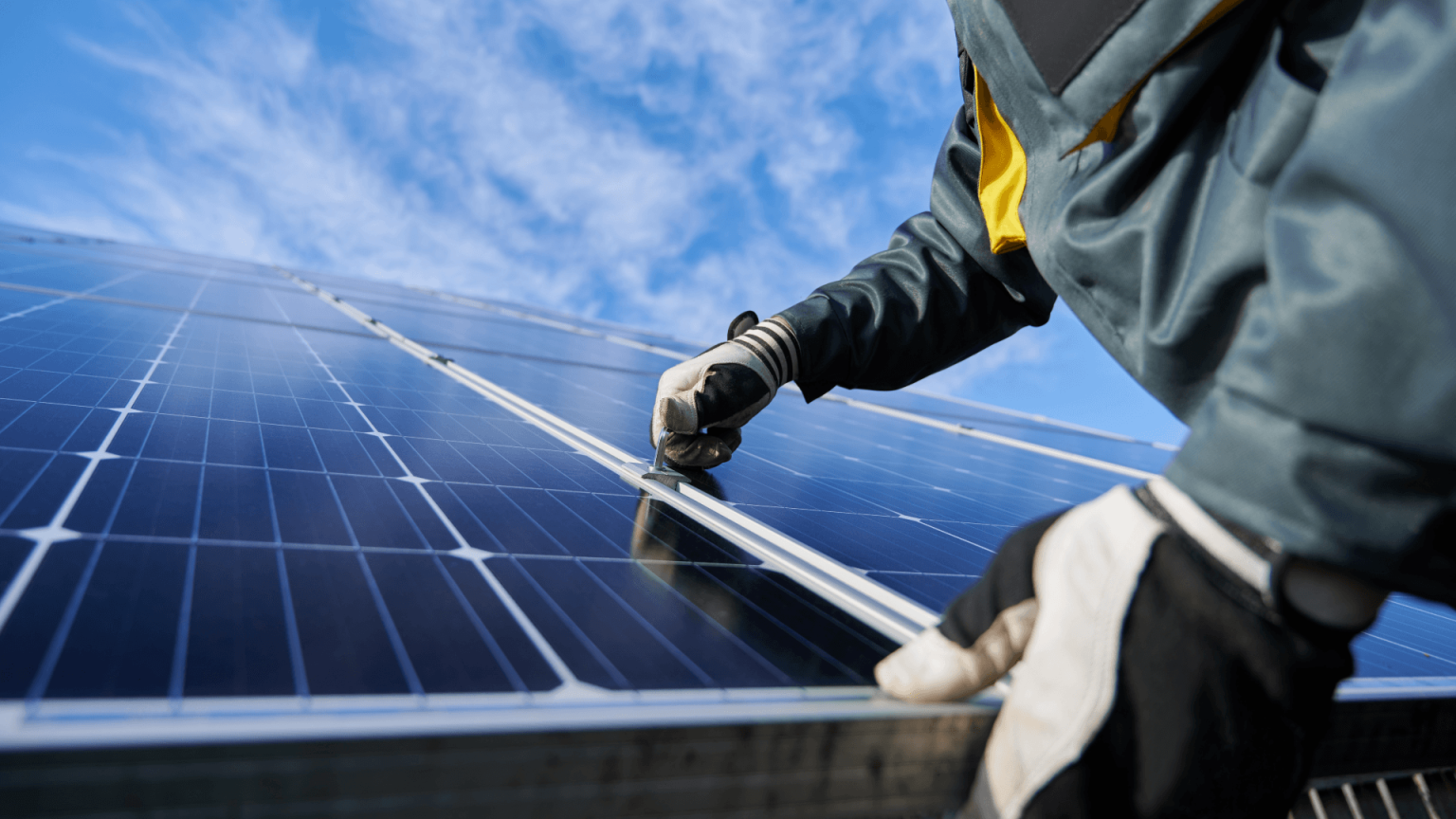 Ein Arbeiter mit Handschuhen installiert eine PV-Anlage.