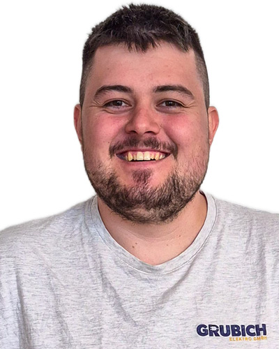 Mann mit kurzem dunklem Haar trägt graues T-Shirt mit Aufdruck 'GRUBICH ELEKTRO GMBH'